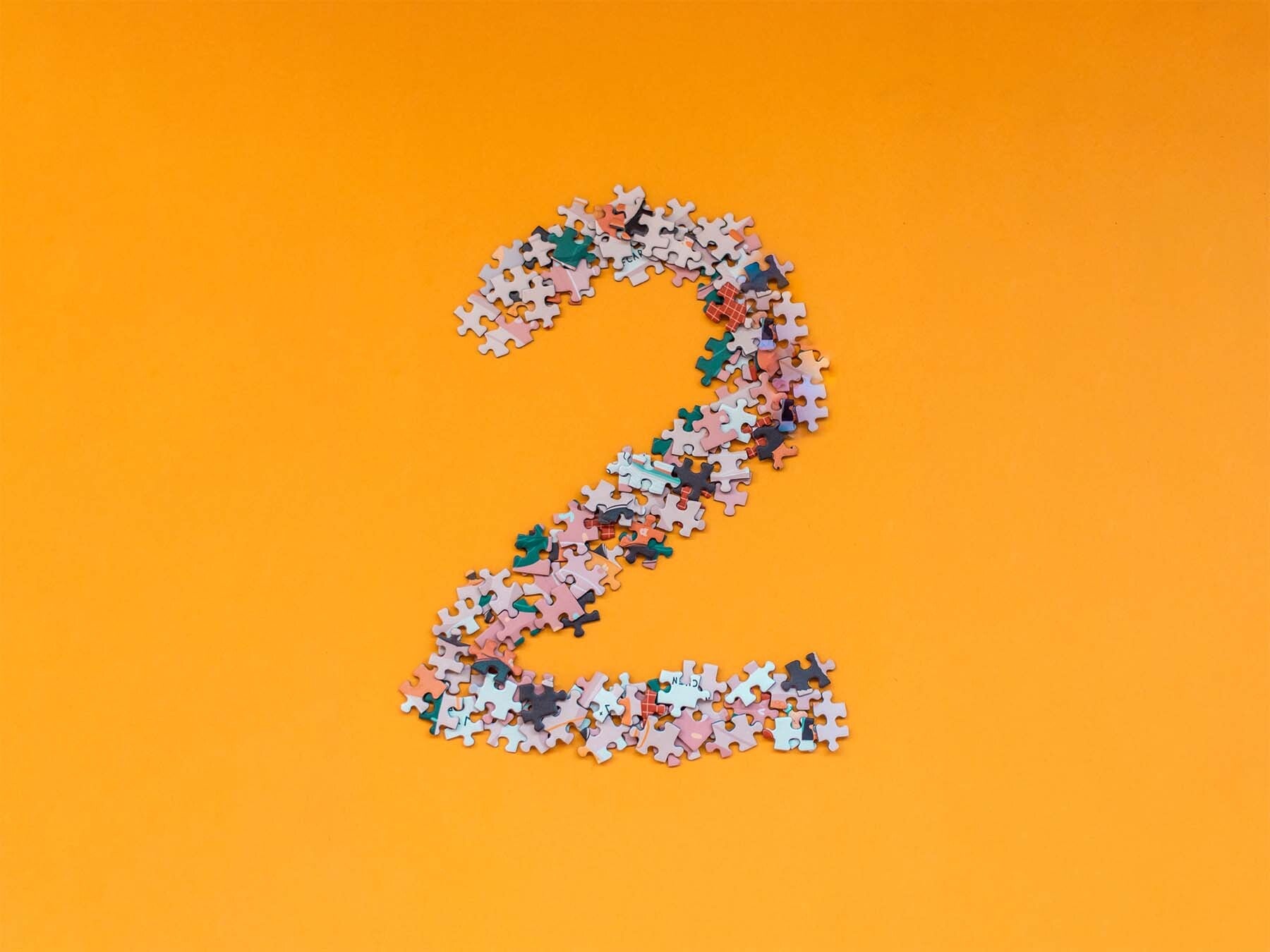 Puzzleteile auf gelbem HIntergrund, die die Zahl 2 formen
